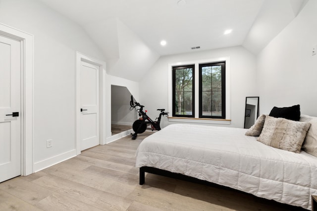 bedroom with light wood-type flooring and vaulted ceiling