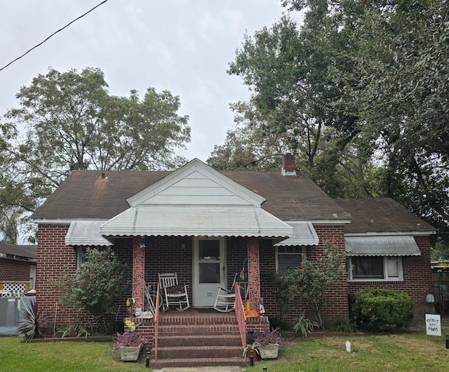 bungalow featuring a porch and a front lawn