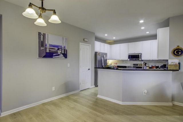 kitchen with backsplash, kitchen peninsula, white cabinetry, and stainless steel appliances