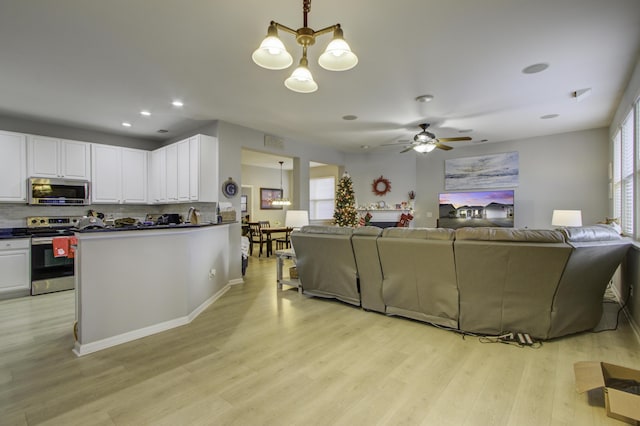 living room with ceiling fan with notable chandelier, plenty of natural light, and light hardwood / wood-style flooring