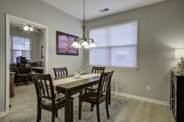 dining space with ceiling fan with notable chandelier and light wood-type flooring