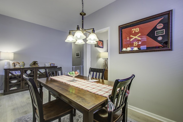 dining space with hardwood / wood-style floors and a notable chandelier