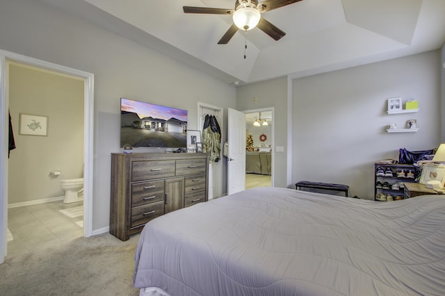 carpeted bedroom with ceiling fan with notable chandelier, a raised ceiling, and ensuite bath