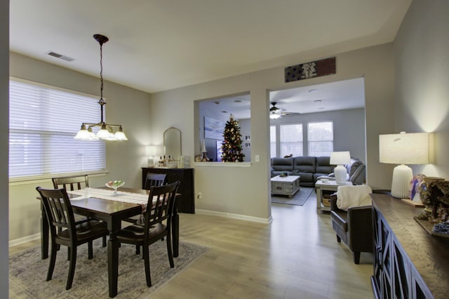 dining area with light hardwood / wood-style floors and ceiling fan with notable chandelier