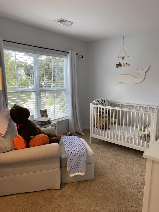 carpeted bedroom featuring a nursery area