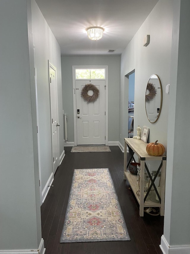 foyer entrance with dark wood-type flooring and baseboards