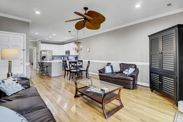 living room with crown molding, light hardwood / wood-style flooring, and ceiling fan with notable chandelier