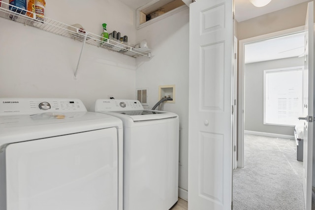 laundry room with independent washer and dryer and light colored carpet