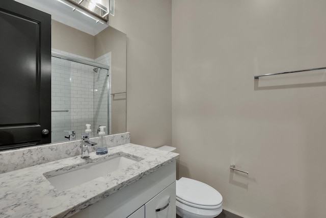 bathroom featuring toilet, an enclosed shower, and vanity