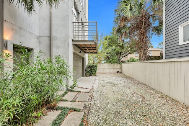 view of yard with a garage and a balcony