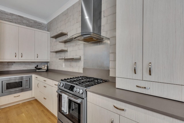 kitchen featuring wall chimney exhaust hood, ornamental molding, appliances with stainless steel finishes, tasteful backsplash, and light hardwood / wood-style floors