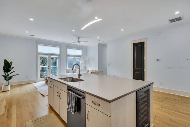 kitchen with pendant lighting, a center island with sink, sink, wine cooler, and light wood-type flooring