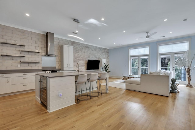 kitchen with white cabinets, french doors, light hardwood / wood-style floors, and wall chimney range hood