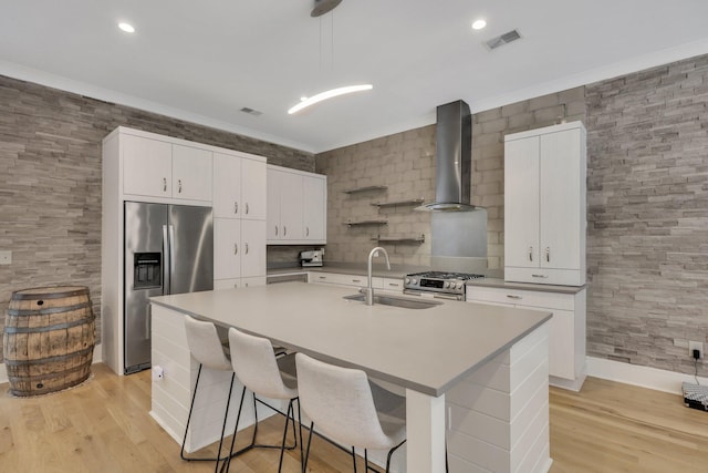 kitchen featuring appliances with stainless steel finishes, wall chimney exhaust hood, sink, white cabinets, and light hardwood / wood-style floors