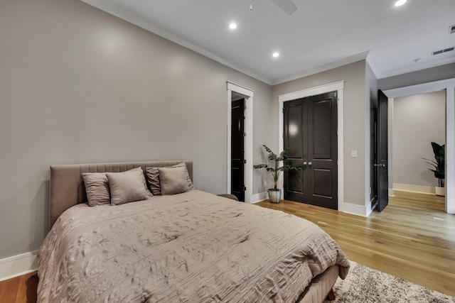 bedroom featuring ceiling fan, a closet, light hardwood / wood-style floors, and ornamental molding