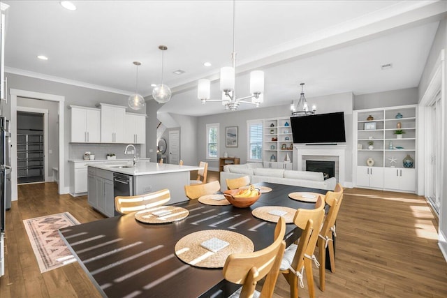 dining area featuring a notable chandelier, sink, dark wood-type flooring, and crown molding