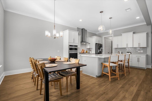 dining room featuring ornamental molding, sink, a notable chandelier, and dark hardwood / wood-style flooring