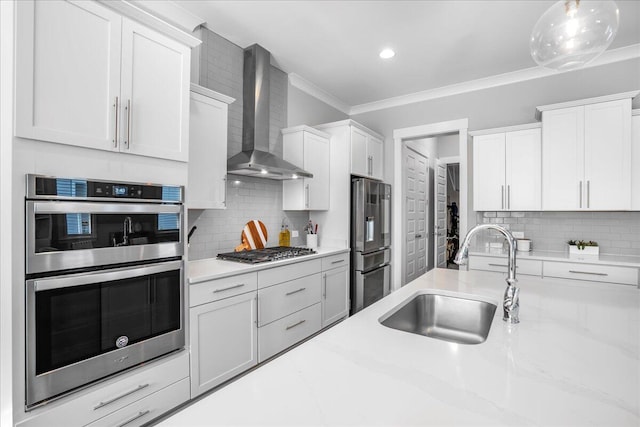 kitchen featuring white cabinets, tasteful backsplash, stainless steel appliances, wall chimney exhaust hood, and sink