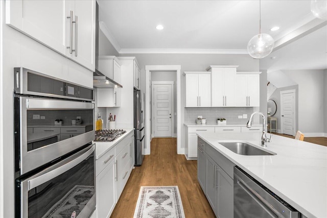 kitchen featuring appliances with stainless steel finishes, sink, white cabinetry, light hardwood / wood-style floors, and pendant lighting