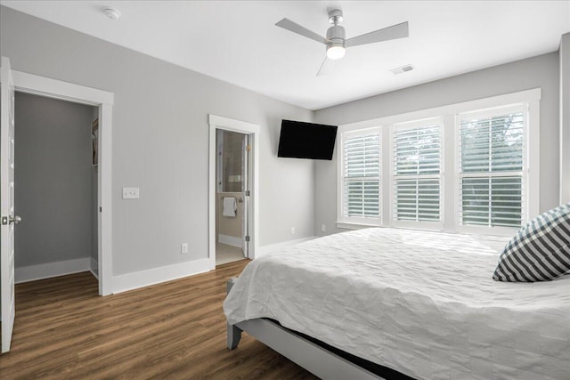 bedroom featuring connected bathroom, dark wood-type flooring, a walk in closet, and ceiling fan