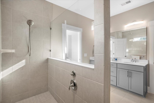 bathroom with vanity, a tile shower, and tile patterned floors