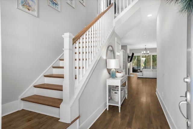 stairs with wood-type flooring and an inviting chandelier