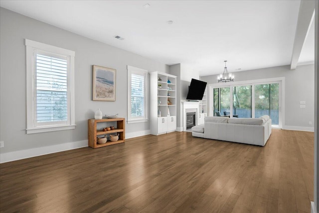 unfurnished living room featuring dark hardwood / wood-style floors, a healthy amount of sunlight, and a chandelier