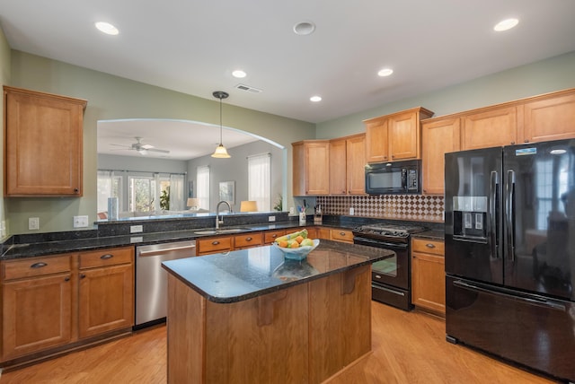 kitchen featuring sink, dark stone countertops, black appliances, decorative light fixtures, and kitchen peninsula