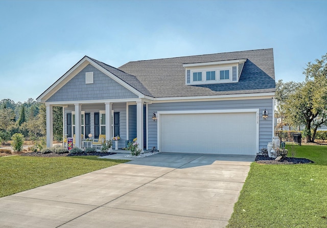 view of front of home featuring roof with shingles, covered porch, an attached garage, a front yard, and driveway