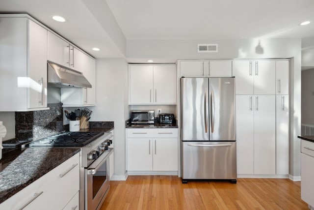 kitchen featuring dark stone countertops, white cabinets, and appliances with stainless steel finishes