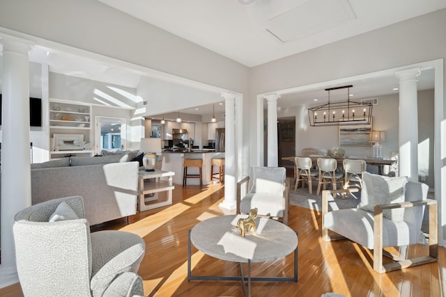 dining space featuring ornate columns, built in features, and wood-type flooring