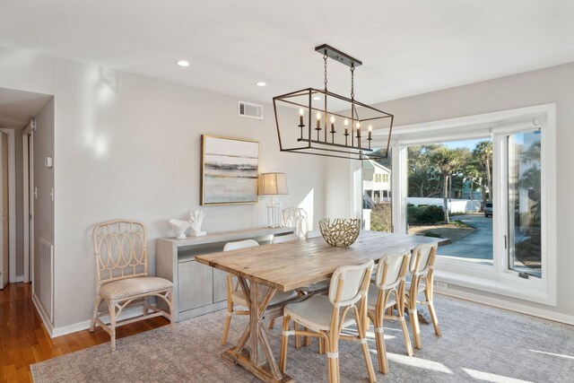 dining area with wood-type flooring and an inviting chandelier