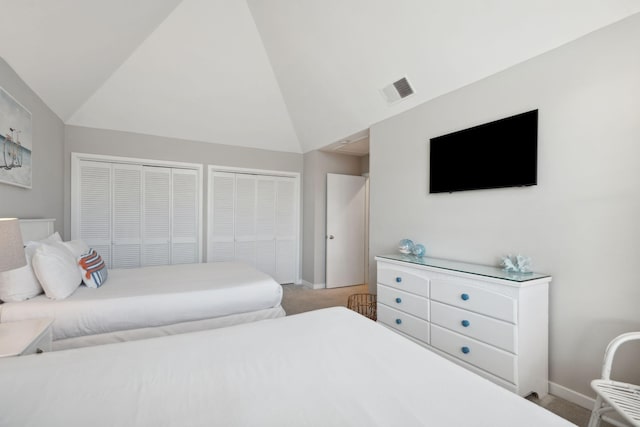 bedroom featuring carpet flooring, vaulted ceiling, and two closets