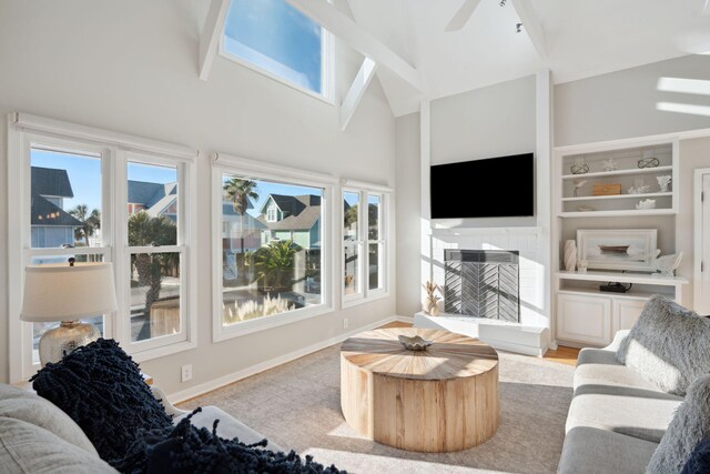 living room featuring built in shelves, vaulted ceiling, a wealth of natural light, and ceiling fan