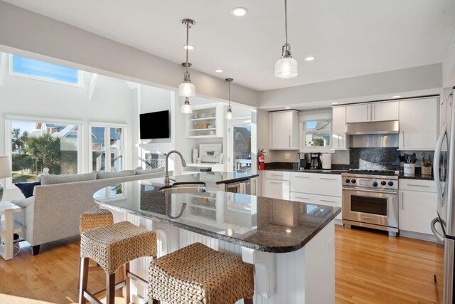 kitchen featuring a skylight, white cabinetry, sink, hanging light fixtures, and stainless steel appliances