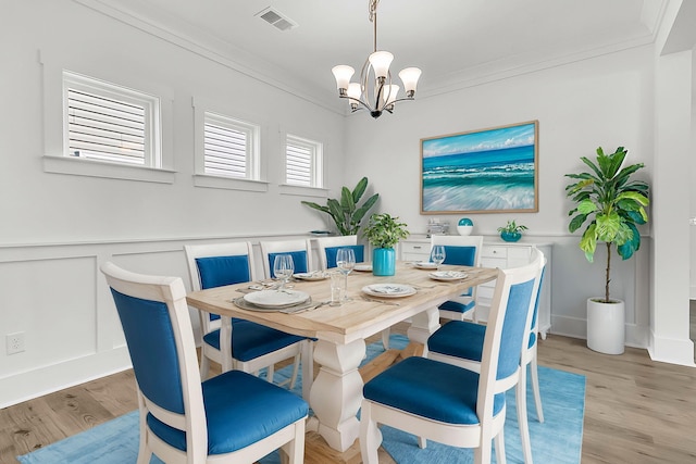 dining space featuring ornamental molding, an inviting chandelier, and light hardwood / wood-style floors