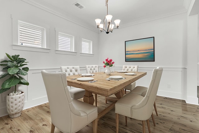 dining space featuring a chandelier, crown molding, and light hardwood / wood-style flooring