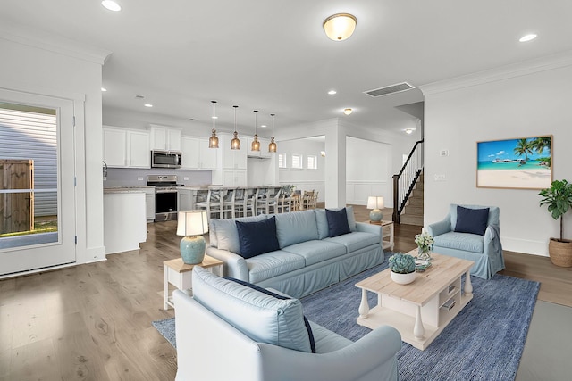 living room featuring light hardwood / wood-style flooring, ornamental molding, and a healthy amount of sunlight