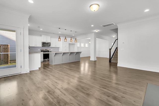 unfurnished living room featuring wood-type flooring and crown molding