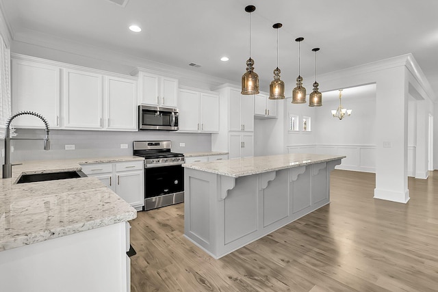 kitchen with light hardwood / wood-style flooring, sink, stainless steel appliances, white cabinets, and a center island