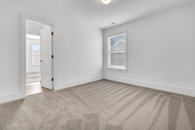 spare room with plenty of natural light and light carpet