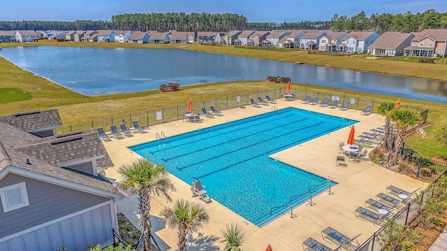 view of pool with a patio, a yard, and a water view