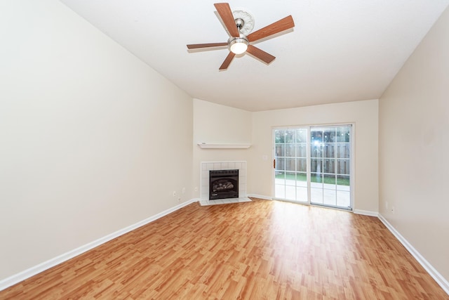 unfurnished living room with a tile fireplace, ceiling fan, and light wood-type flooring