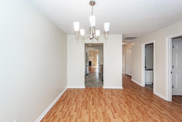 unfurnished dining area featuring hardwood / wood-style floors, a notable chandelier, and a textured ceiling