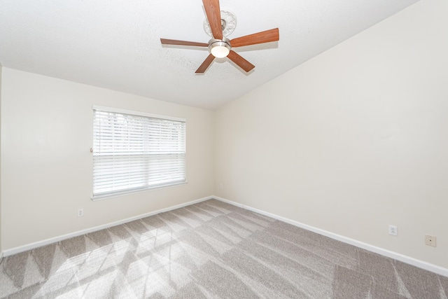 empty room featuring ceiling fan, light colored carpet, lofted ceiling, and a textured ceiling