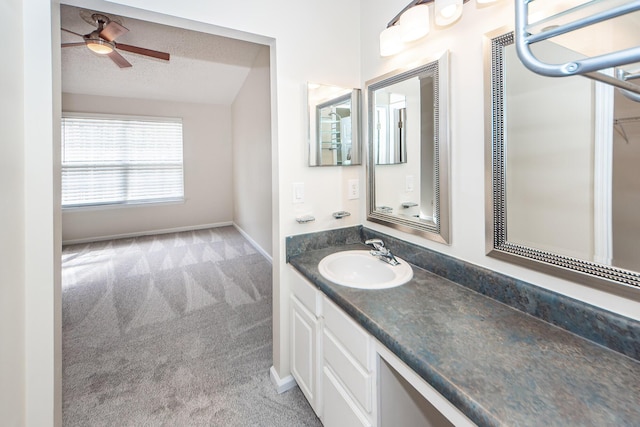 bathroom with vanity, vaulted ceiling, ceiling fan, and a textured ceiling