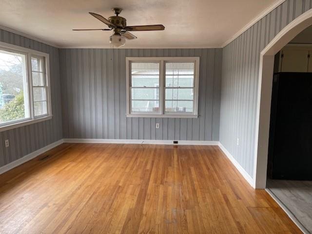 empty room featuring crown molding, light wood-type flooring, and ceiling fan