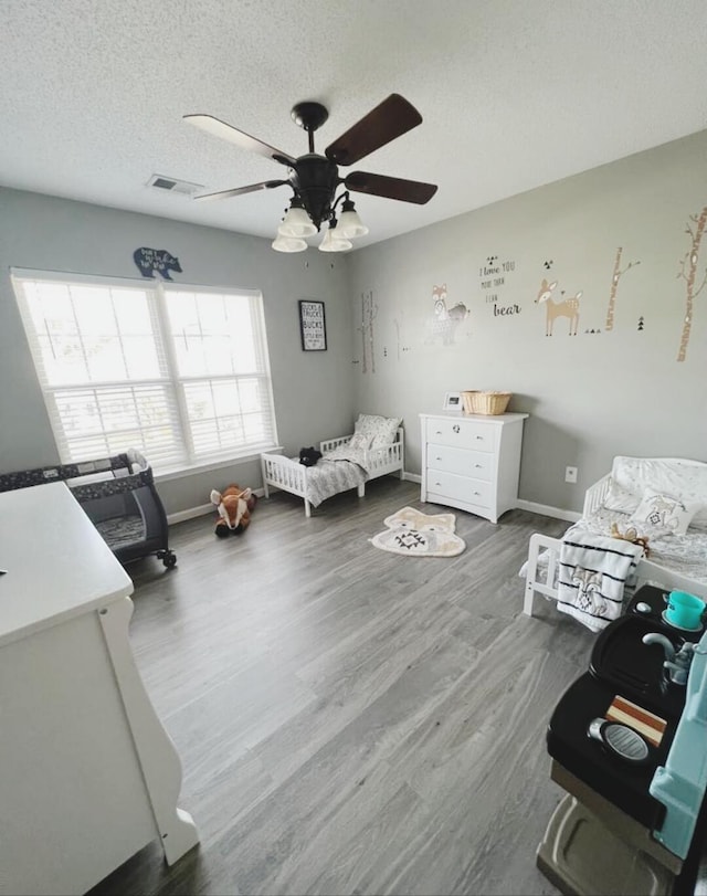 bedroom featuring ceiling fan, hardwood / wood-style flooring, and a textured ceiling