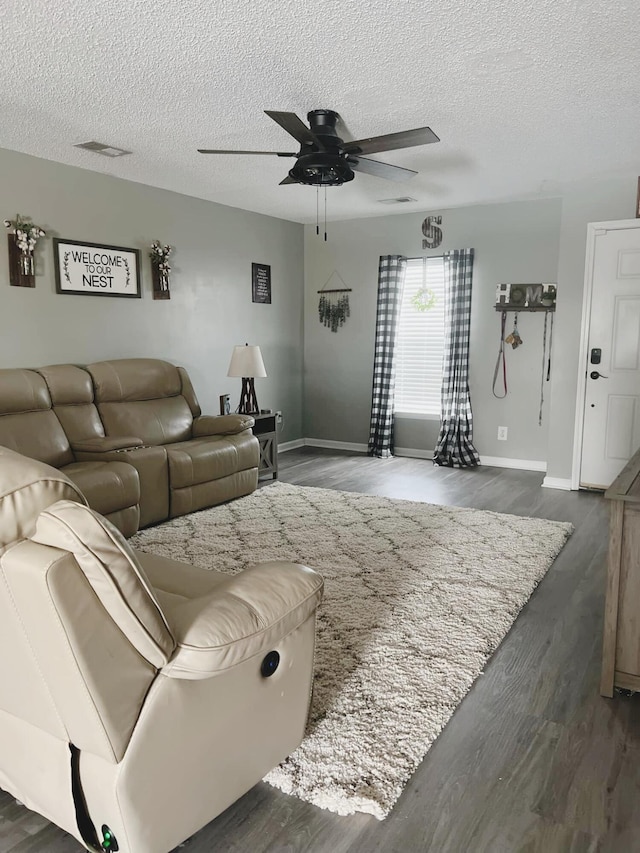 living room with dark hardwood / wood-style flooring, a textured ceiling, and ceiling fan