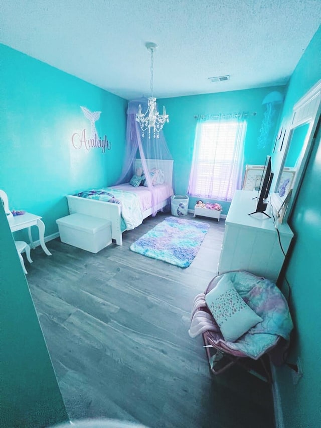 bedroom featuring an inviting chandelier, hardwood / wood-style floors, and a textured ceiling